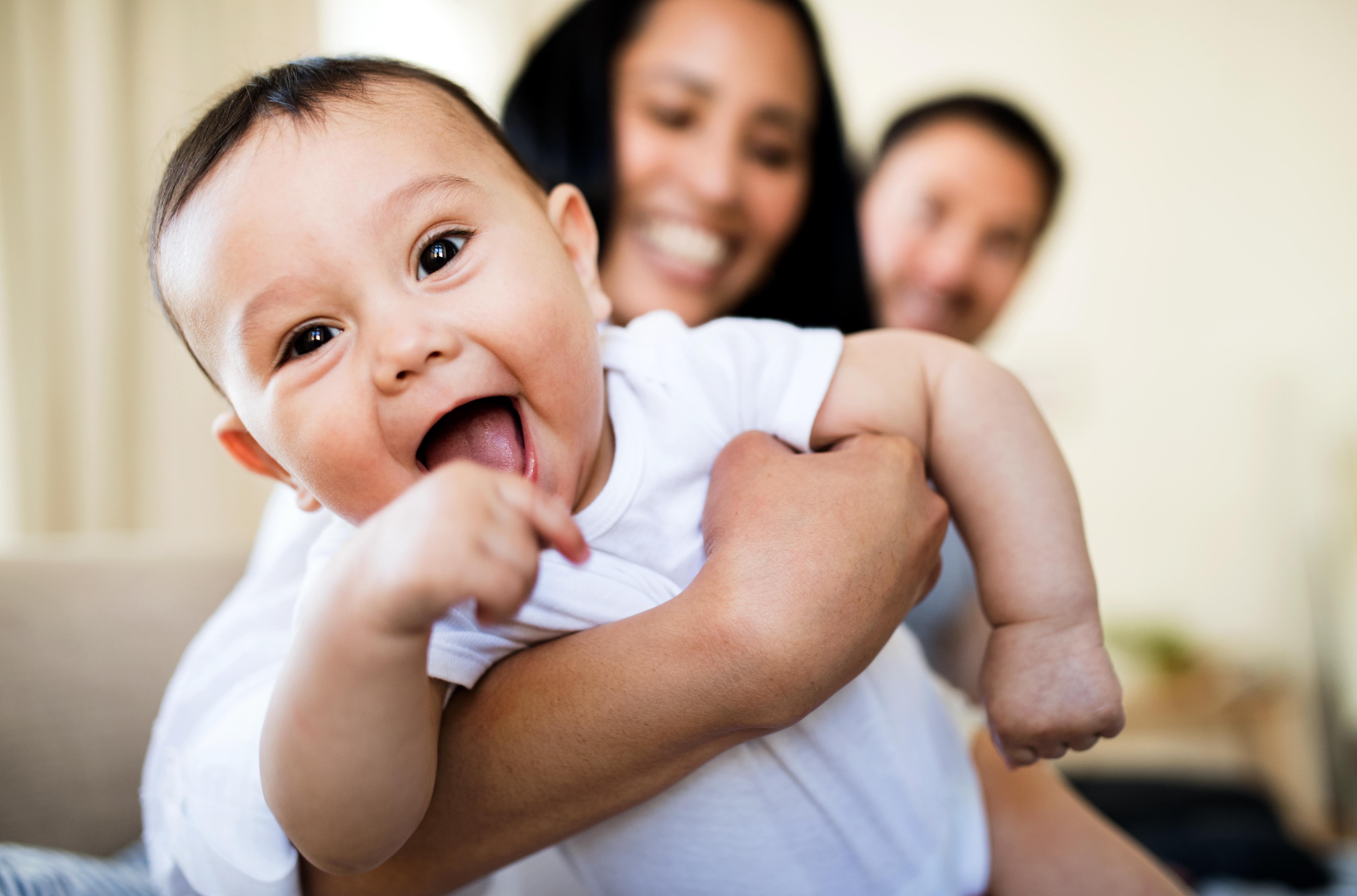 Image depicts and mother and father holding their baby